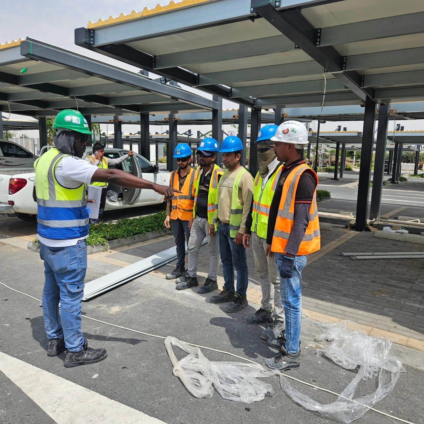 Austin directing a crew during a safety briefing beside a steel structure on a Qatar project