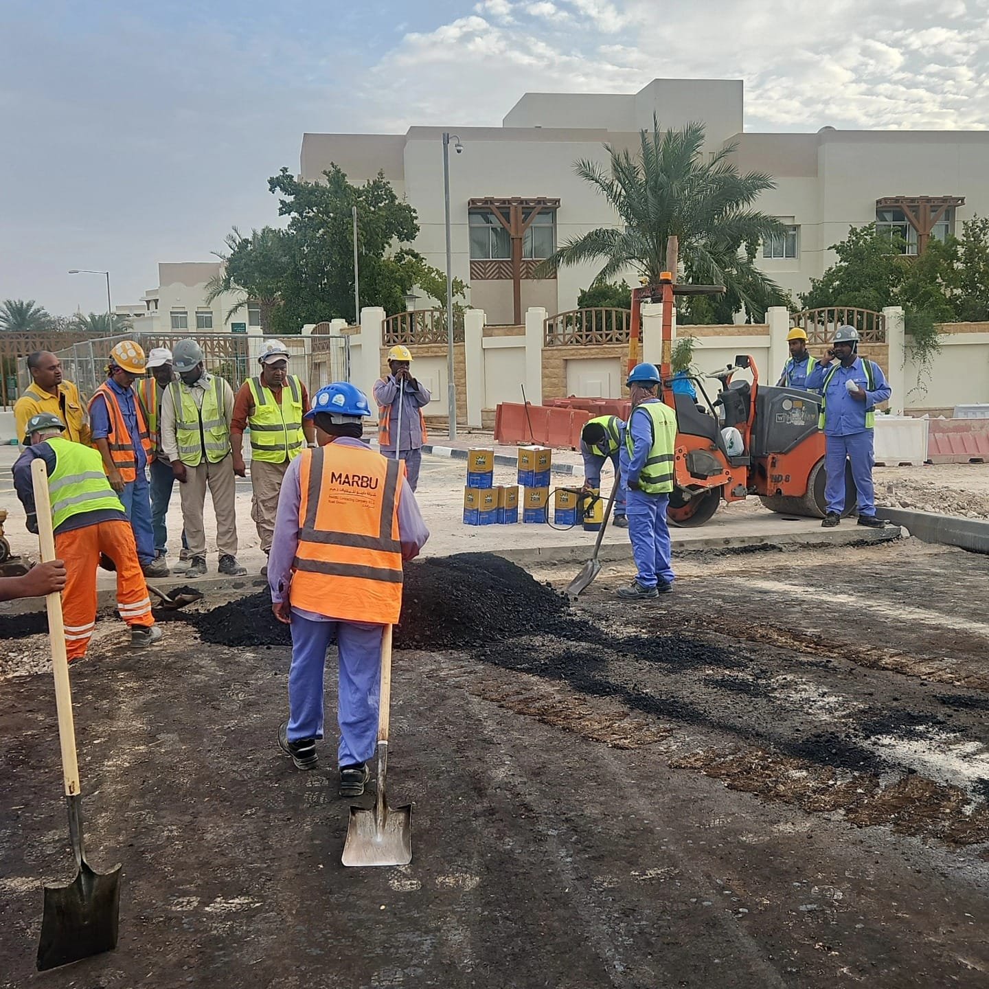 Road construction crew laying and levelling asphalt on a Qatar street project