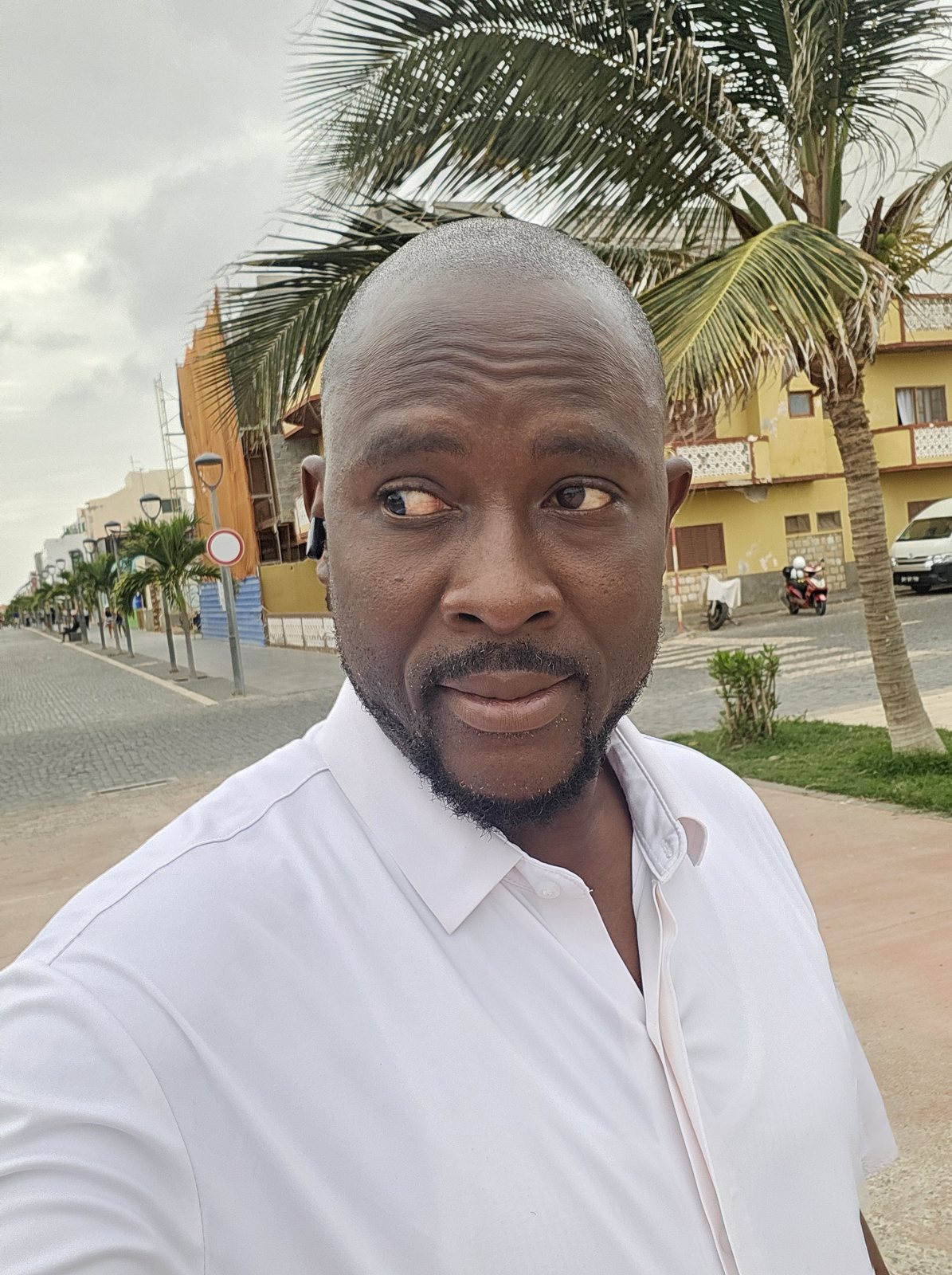 Austin Obule Emovworho in a crisp white shirt on a seaside promenade
