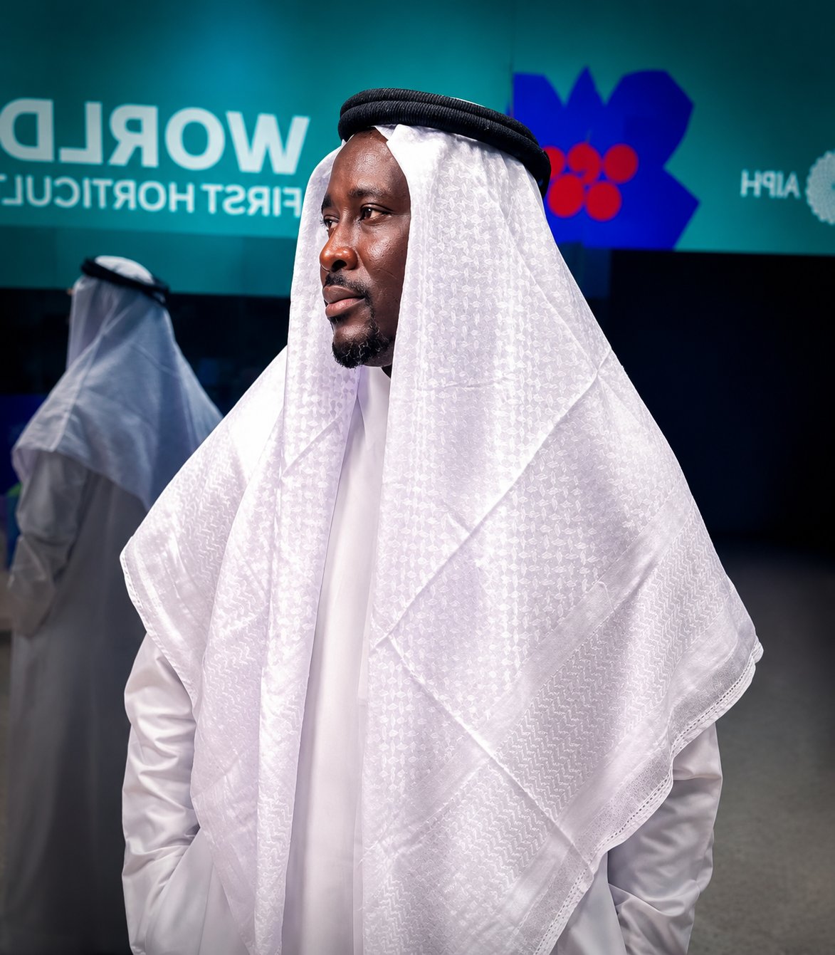 Austin Obule Emovworho in a traditional white thobe and keffiyeh at a professional event in Qatar