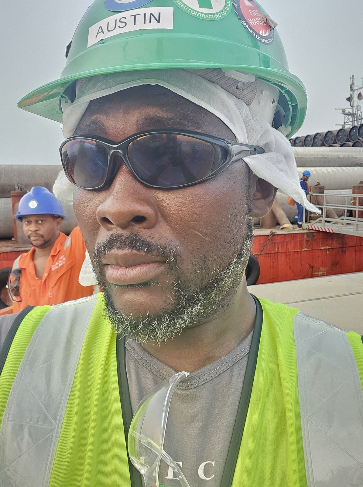 Austin wearing safety helmet and glasses supervising heavy-lift pipe operations on site