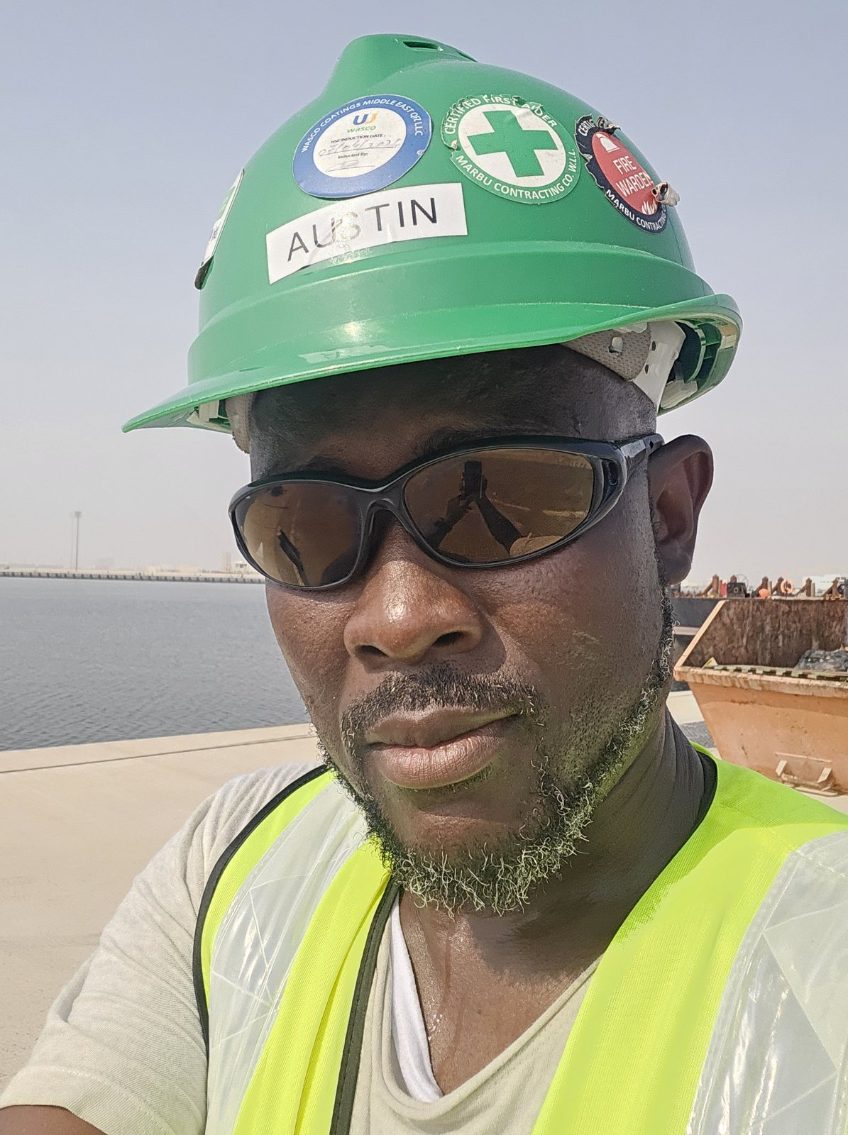Austin in green HSE helmet and hi-vis vest at a port construction site in Qatar
